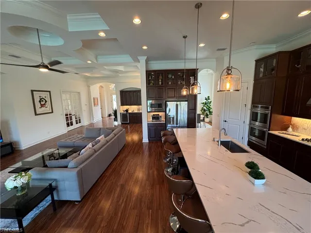 a kitchen with stainless steel appliances kitchen island granite countertop a sink dishwasher stove and a refrigerator with wooden floor