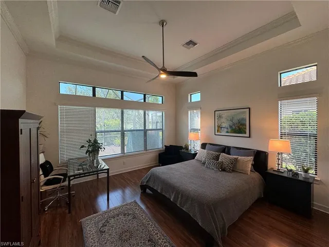 a bedroom with a bed flat screen tv and windows