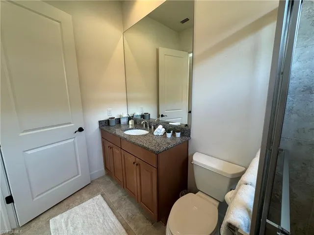 a bathroom with a granite countertop toilet sink and mirror