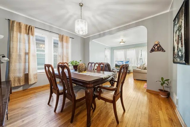 a kitchen with stainless steel appliances kitchen island granite countertop a refrigerator a stove a sink a dining table and chairs with wooden floor