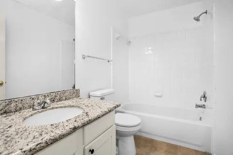 a bathroom with a granite countertop sink a toilet and bathtub