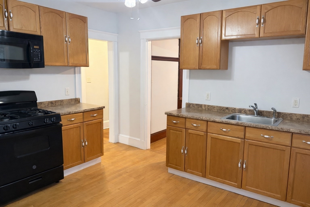 14 Walter Street, Unit 1 Boston, MA 02131 - Photo 7 of 14 a kitchen with granite countertop a sink stove and microwave