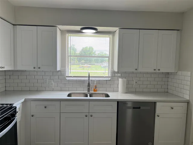a kitchen with stainless steel appliances white cabinets and a window