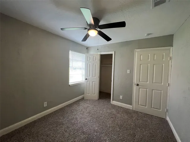 an empty room with ceiling fan and window
