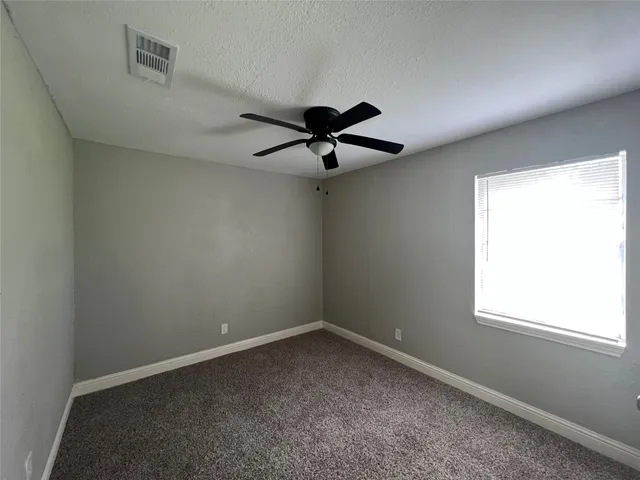 an empty room with a window and a ceiling fan