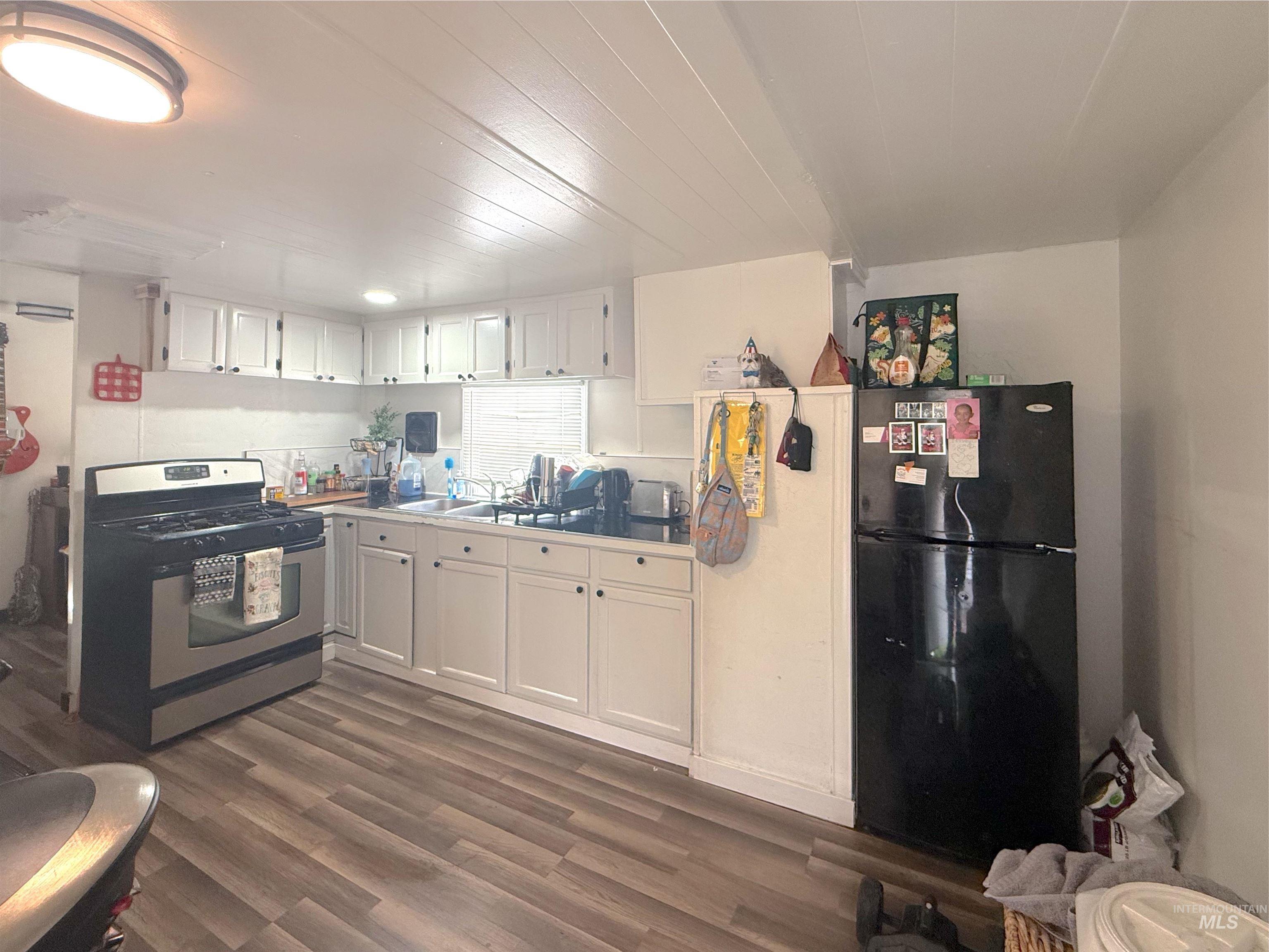 6728 West Fairview Avenue, Unit 24 Boise, ID 83704 - Photo 5 of 9 Kitchen with stainless steel gas range oven, freestanding refrigerator, white cabinetry, dark wood-type flooring, and light countertops