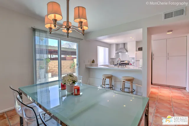 a room with stainless steel appliances kitchen island granite countertop a stove a sink a dining table and chairs