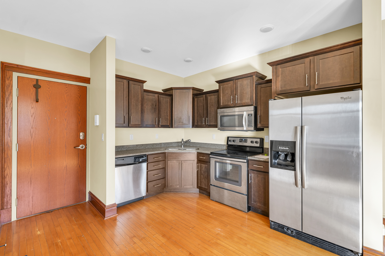 41 East University Avenue Champaign, IL 61820 - Photo 42 of 83 a kitchen with granite countertop stainless steel appliances a refrigerator cabinets and wooden floor