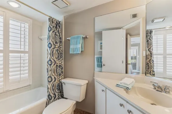 a bathroom with a granite countertop toilet a sink a mirror a bathtub and shower