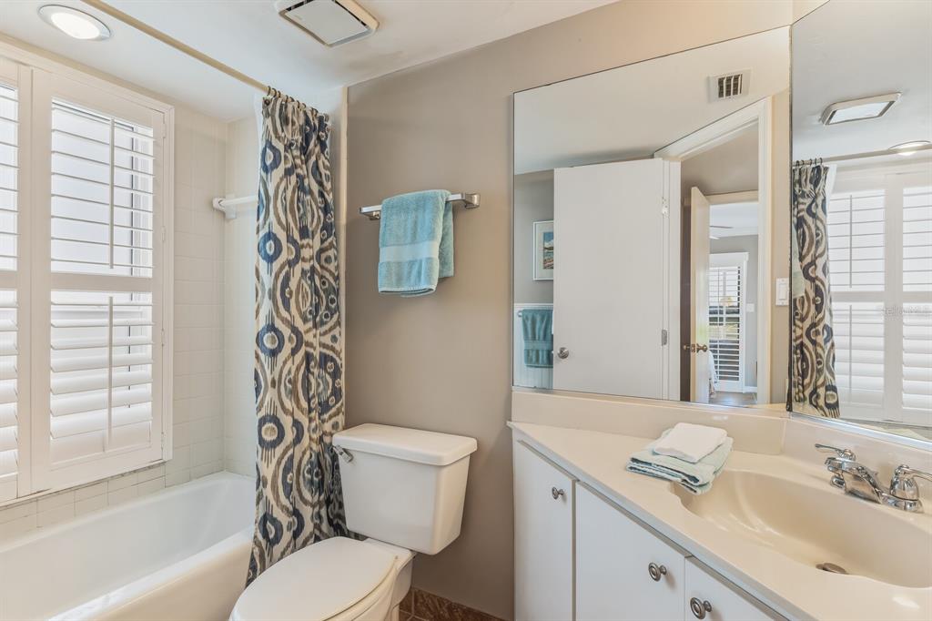 5000 Gasparilla Road, Unit DC107 Boca Grande, FL 33921 - Photo 11 of 30 a bathroom with a granite countertop toilet a sink a mirror a bathtub and shower