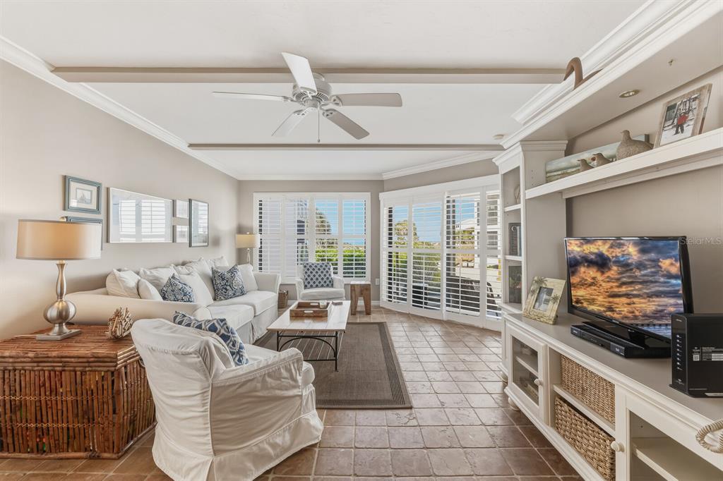 5000 Gasparilla Road, Unit DC107 Boca Grande, FL 33921 - Photo 4 of 30 a living room with furniture a flat screen tv and a floor to ceiling window