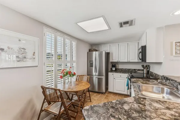 a kitchen with stainless steel appliances granite countertop a stove a refrigerator a sink a dining table and chairs with wooden floor