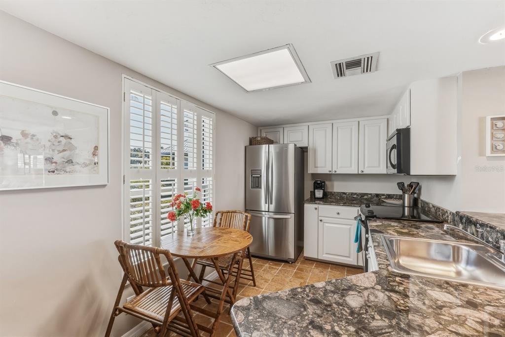 5000 Gasparilla Road, Unit DC107 Boca Grande, FL 33921 - Photo 6 of 30 a kitchen with stainless steel appliances granite countertop a stove a refrigerator a sink a dining table and chairs with wooden floor