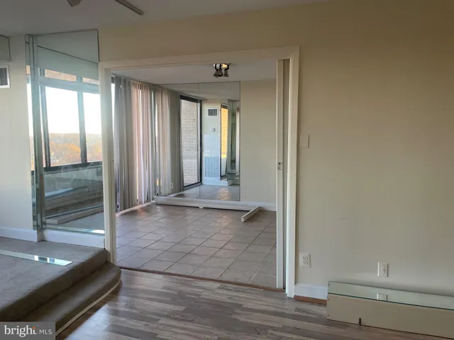 a view of a hallway to an empty room and window