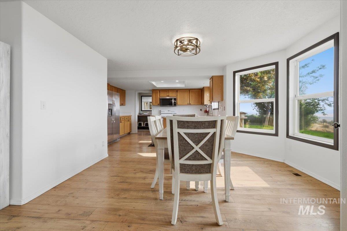 24440 Kenridge Road Caldwell, ID 83607 - Photo 19 of 48 Dining area featuring wood-finish flooring, a contemporary ceiling fixture, and a bay window with dark trim