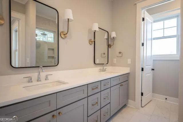 a bathroom with a double vanity sink mirror and next to a window