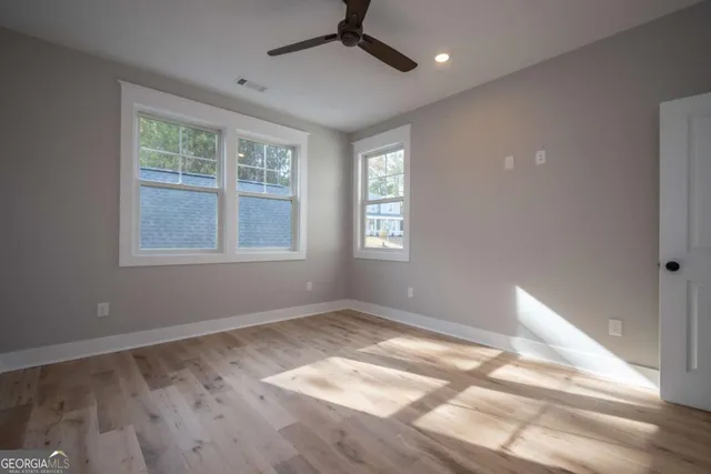 a view of empty room with wooden floor and fan
