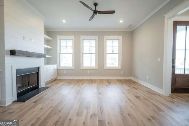 a view of an empty room with wooden floor fireplace and a window