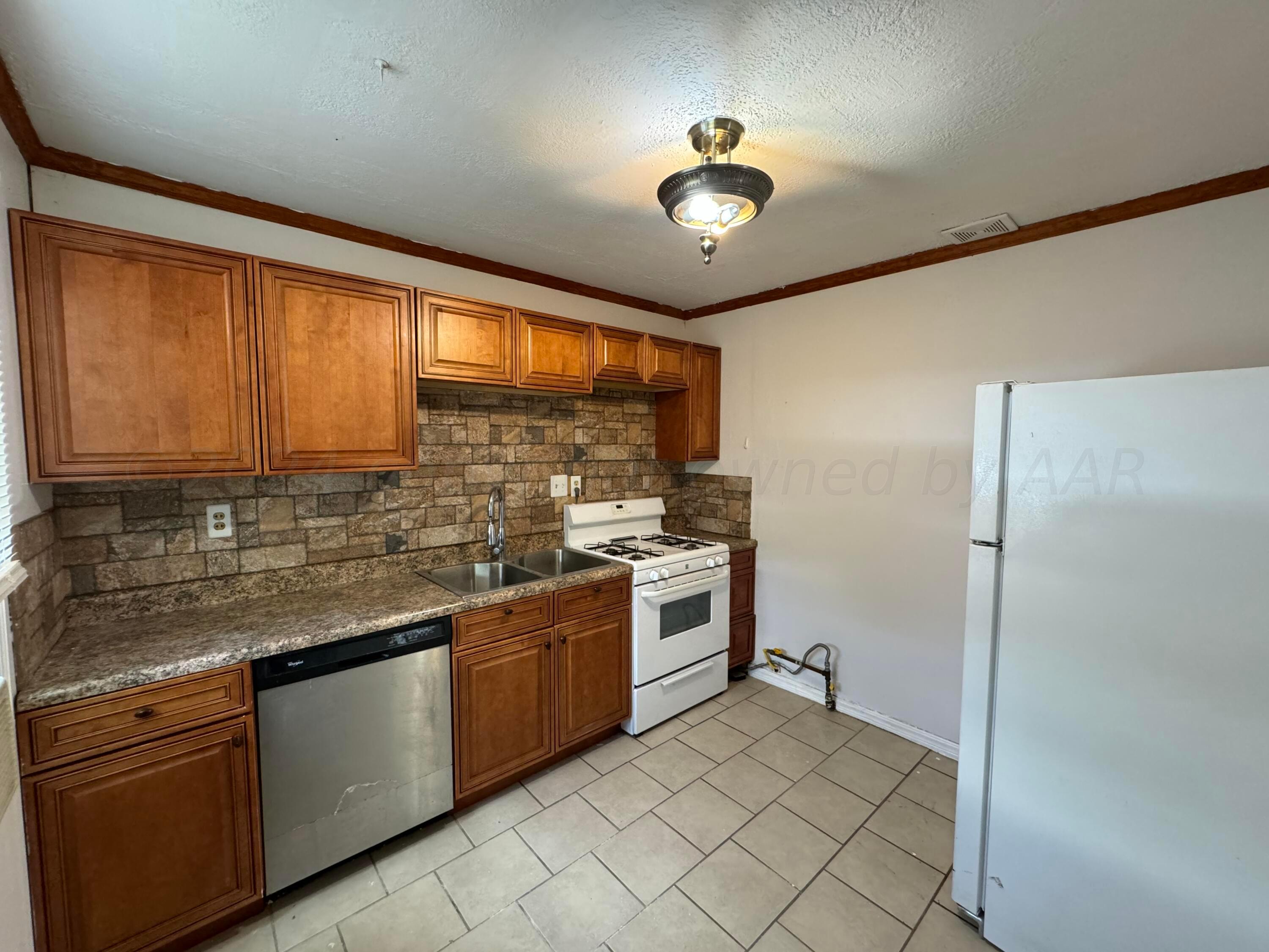 4119 Parker Street Amarillo, TX 79110 - Photo 2 of 9 a kitchen with stainless steel appliances granite countertop a sink stove and refrigerator