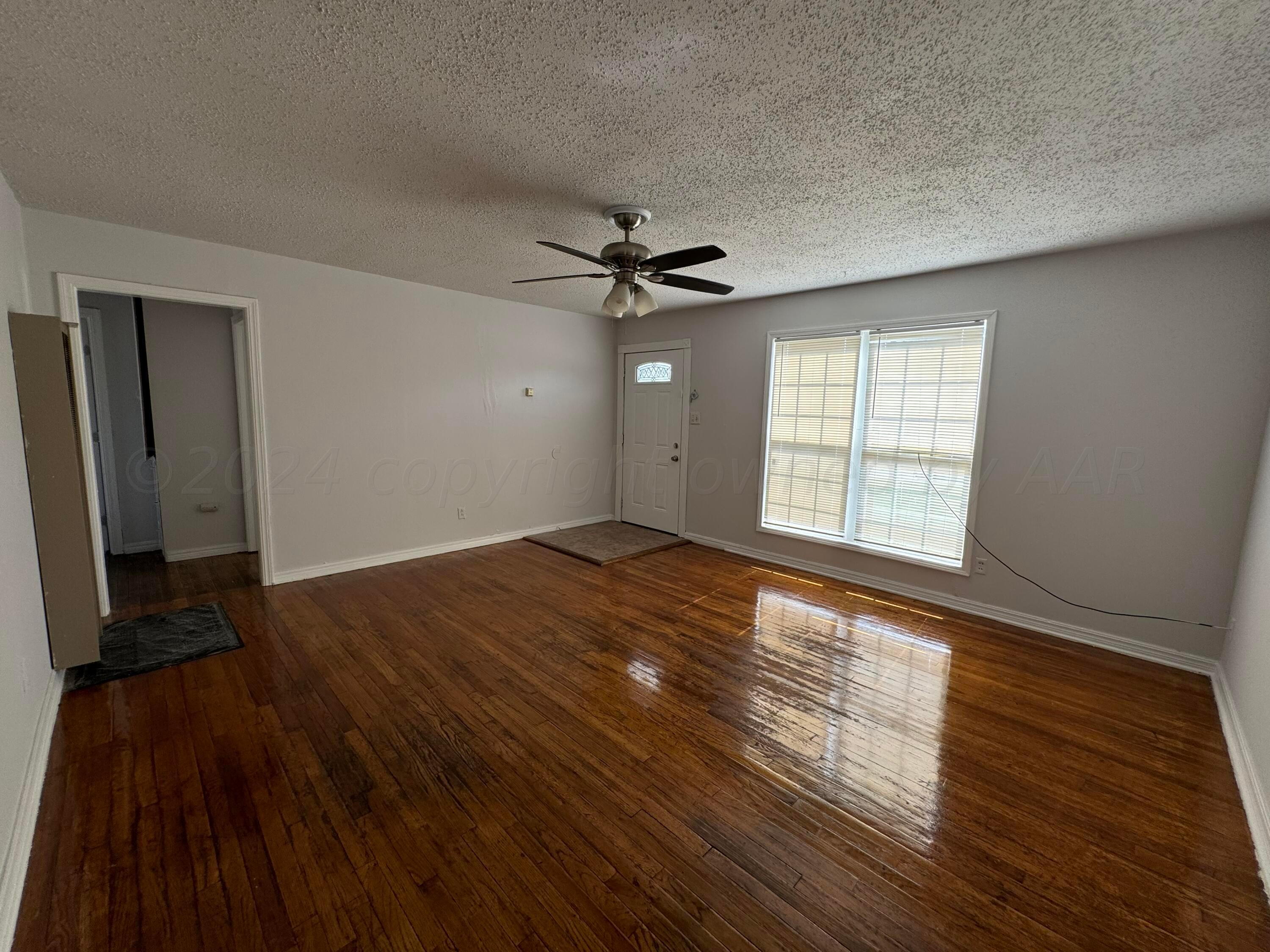 4119 Parker Street Amarillo, TX 79110 - Photo 4 of 9 wooden floor in an empty room with a window