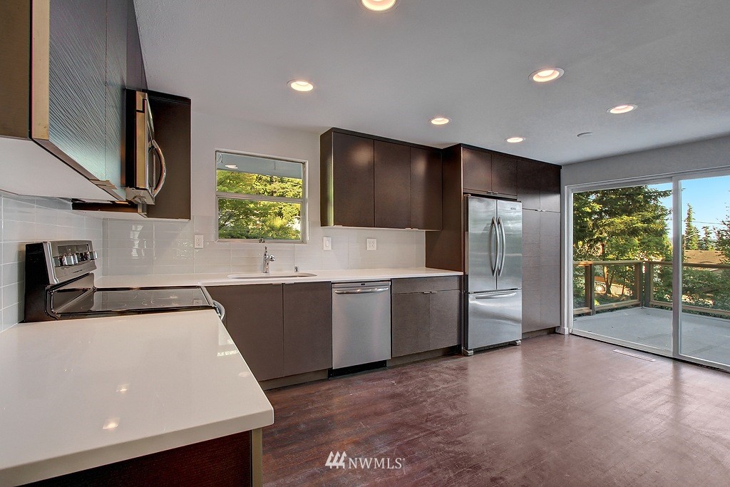 24320 4th Place West Bothell, WA 98021 - Photo 3 of 24 a large kitchen with stainless steel appliances a large counter top a stove a chimney a sink and a refrigerator
