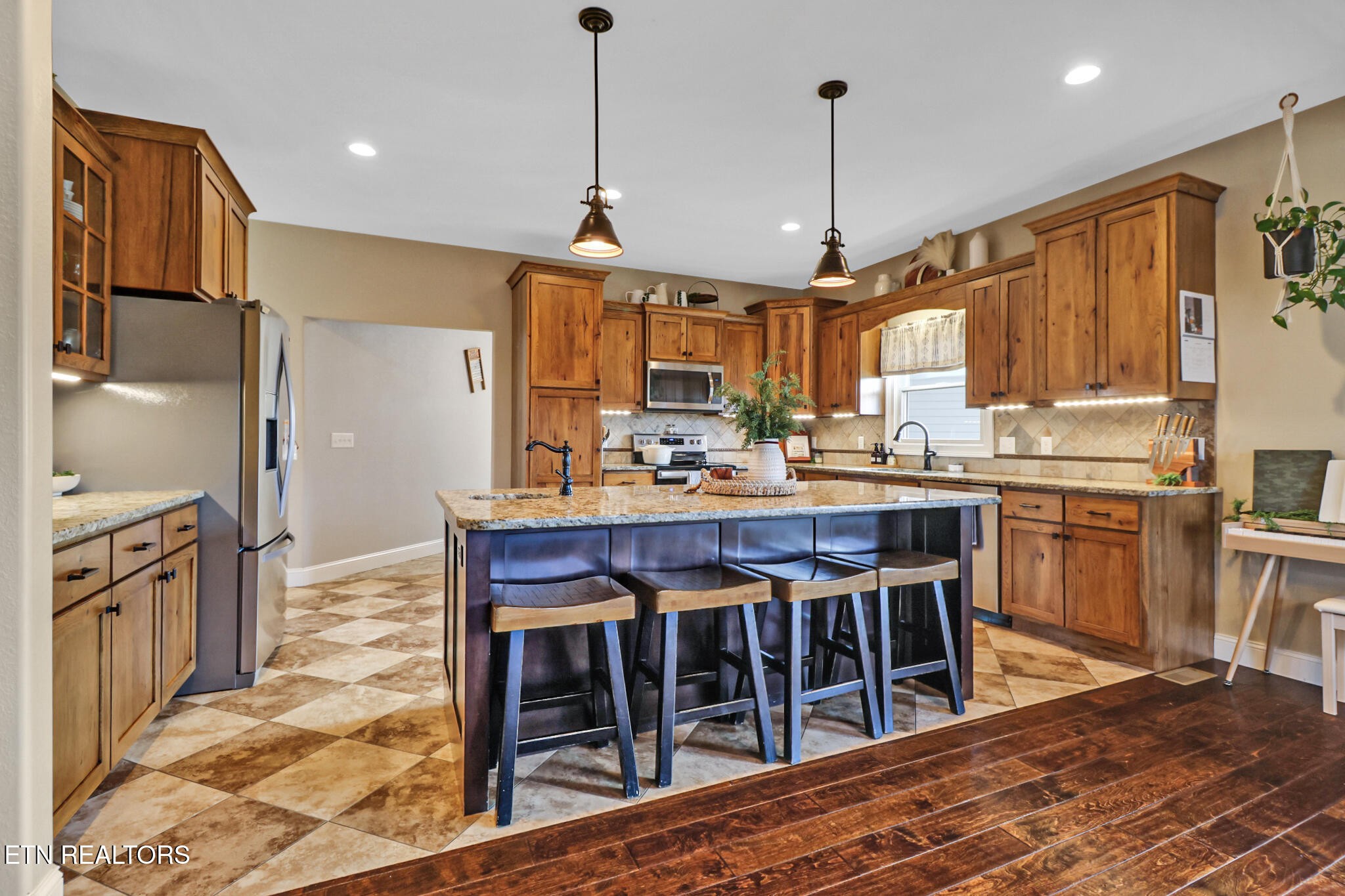 370 Randolph Road Crossville, TN 38571 - Photo 18 of 60 a kitchen with stainless steel appliances granite countertop a stove a sink dishwasher a refrigerator and a dining table with wooden floor
