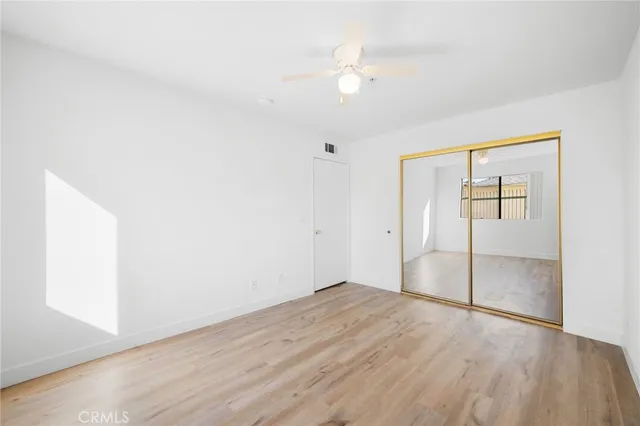 an empty room with wooden floor and fan