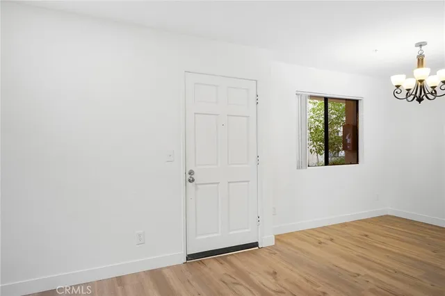 an empty room with wooden floor closet and windows