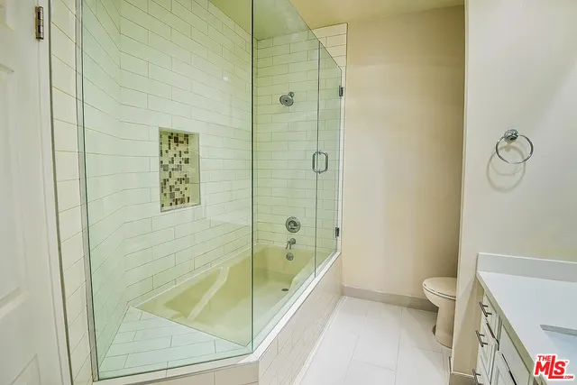 a bathroom with a granite countertop bathtub shower and toilet