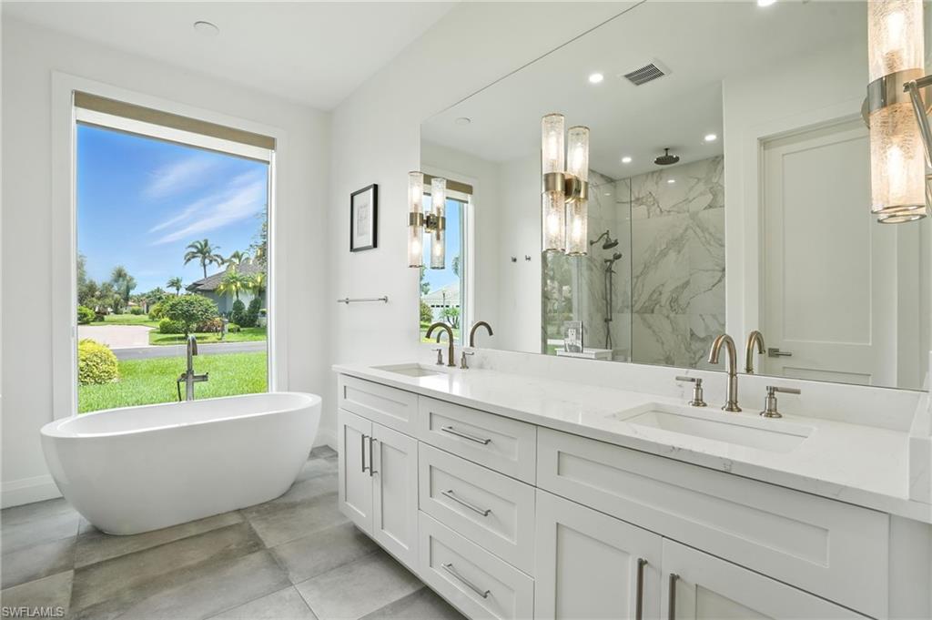 581 Wedgewood Way Naples, FL 34119 - Photo 14 of 33 a bathroom with a large tub a sink and a large window