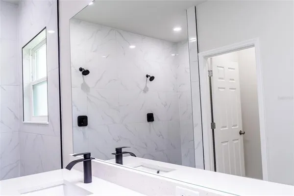 a bathroom with a sink a toilet a mirror and shower