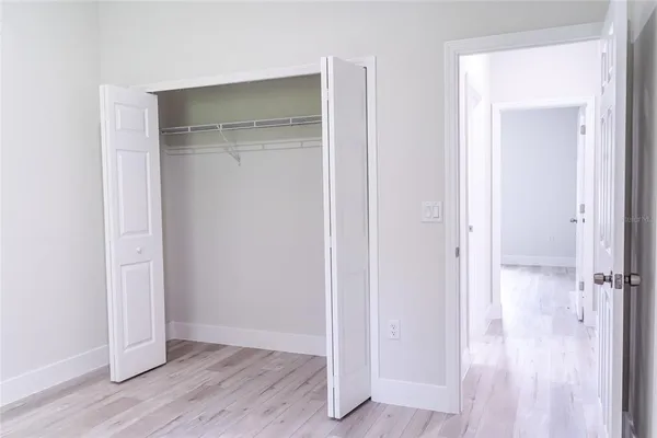 an empty room with wooden floor & closet area