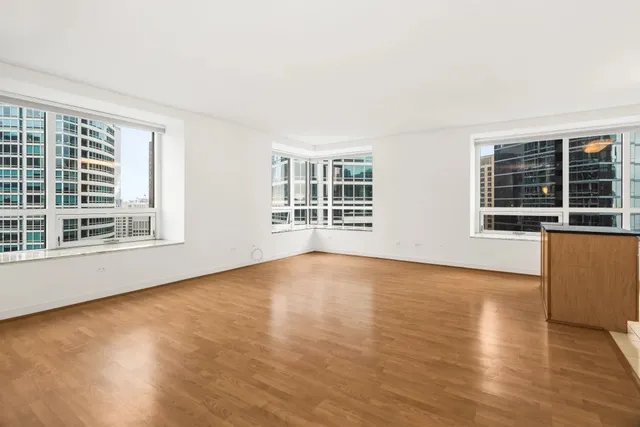 a view of an empty room with wooden floor and windows