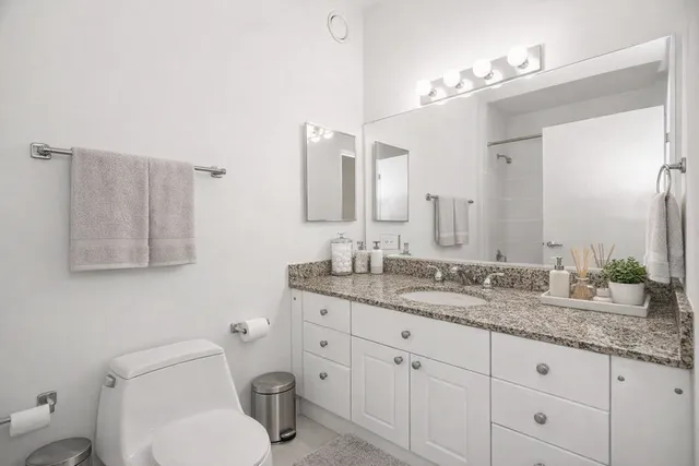 a bathroom with a granite countertop toilet sink and mirror