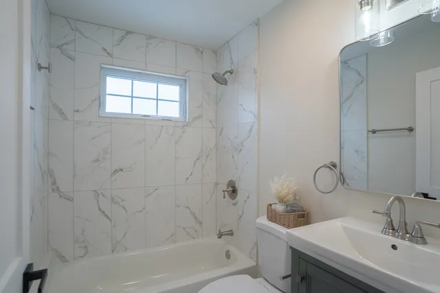 a bathroom with a toilet sink vanity tub and shower