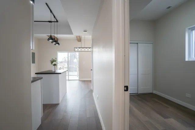 a view of a hallway with wooden floor and a bathroom
