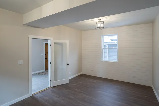 an empty room with wooden floor chandelier and windows