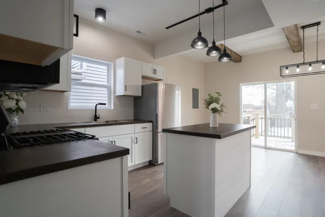 a kitchen with stainless steel appliances granite countertop a sink a stove a refrigerator a microwave oven with white cabinets