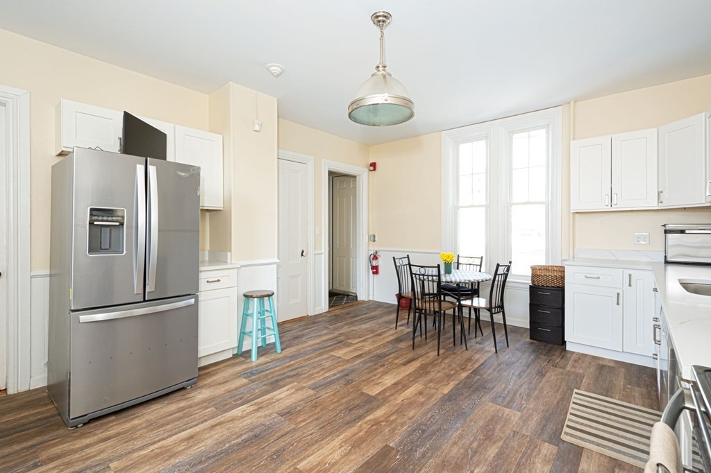 56 William Street Worcester, MA 01609 - Photo 9 of 37 a kitchen with stainless steel appliances a refrigerator a stove a dining table and chairs with wooden floor