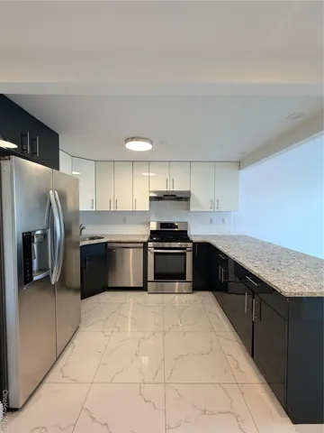 a kitchen with stainless steel appliances granite countertop a stove a sink and a refrigerator