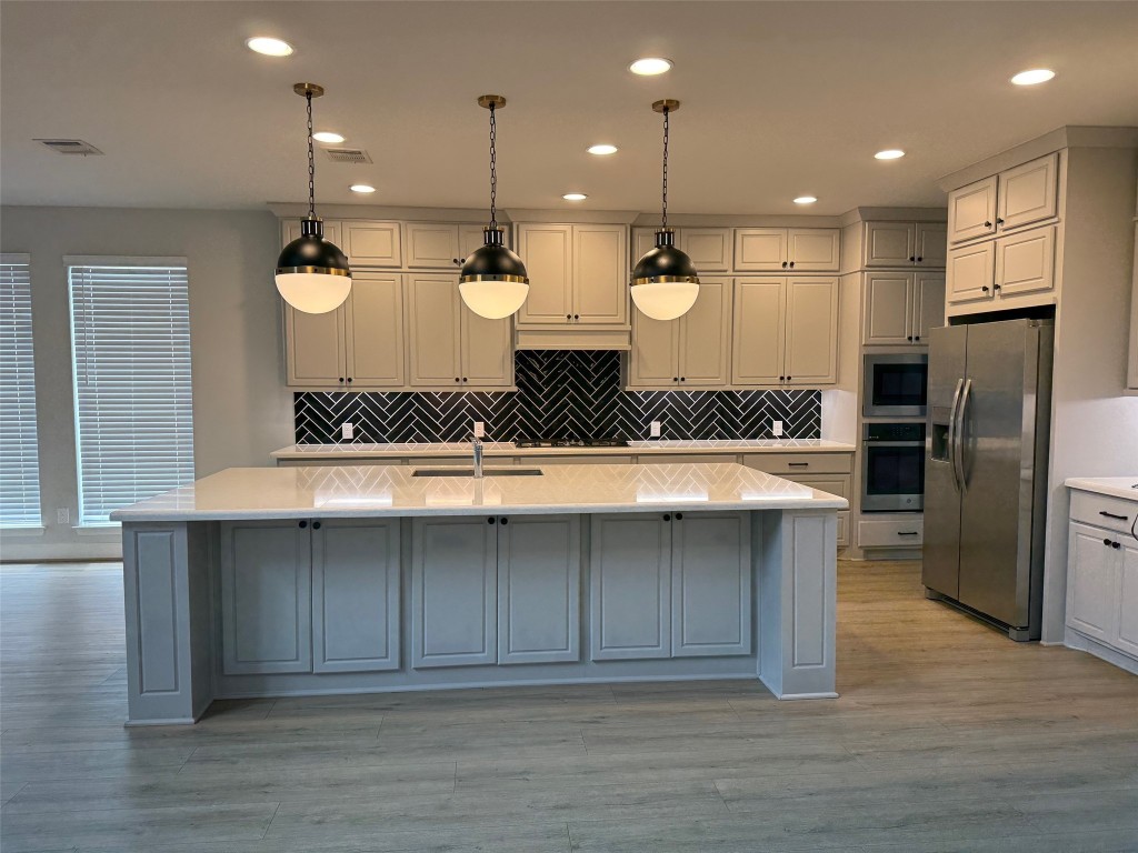 29819 Breezy Pnes Loop Fulshear, TX 77441 - Photo 25 of 50 a large kitchen with a large counter top stainless steel appliances and wooden floor