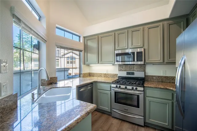 a kitchen with granite countertop a stove a sink and refrigerator