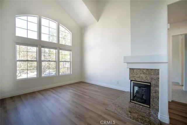 an empty room with wooden floor fireplace and windows