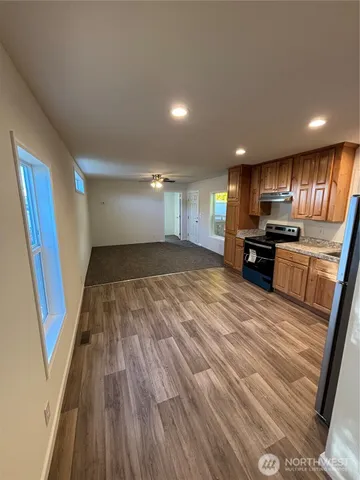 a view of empty room with kitchen and wooden floor