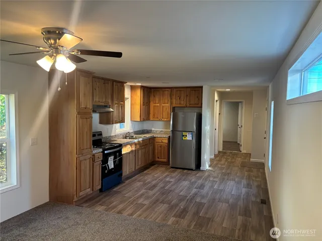 a kitchen with stainless steel appliances granite countertop a refrigerator a sink dishwasher a stove and a dining table with wooden floor