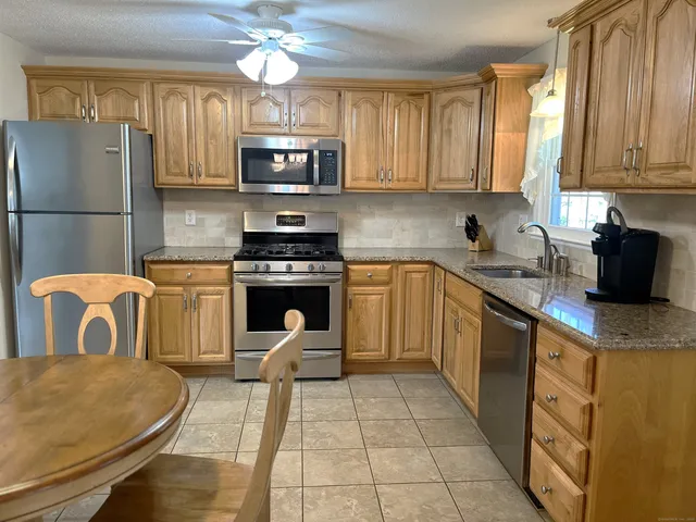 a kitchen with stainless steel appliances granite countertop a stove top oven a sink a dining table and chairs