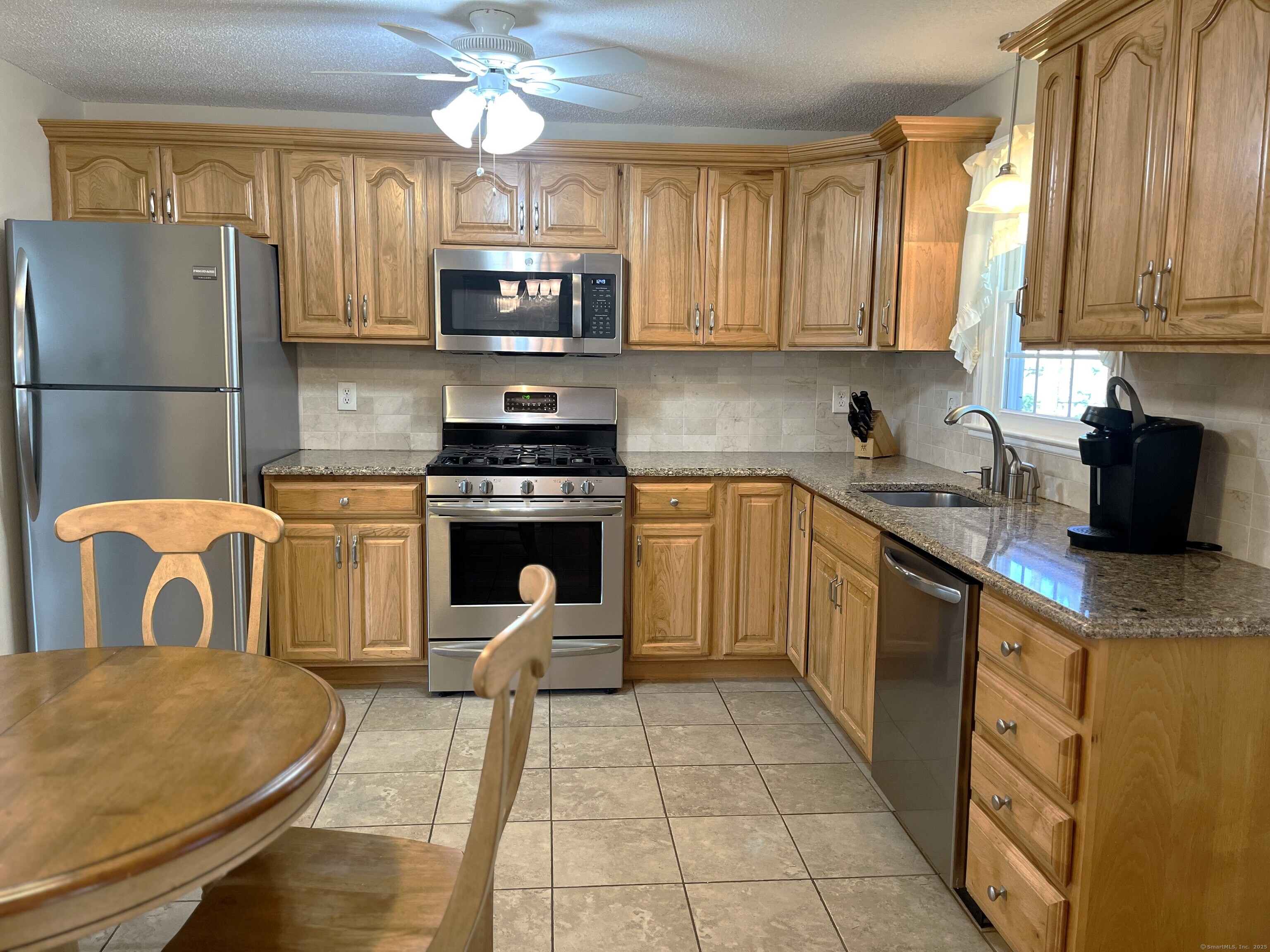 20 Fawn Ridge Drive North Haven, CT 06473 - Photo 7 of 27 a kitchen with stainless steel appliances granite countertop a stove top oven a sink a dining table and chairs