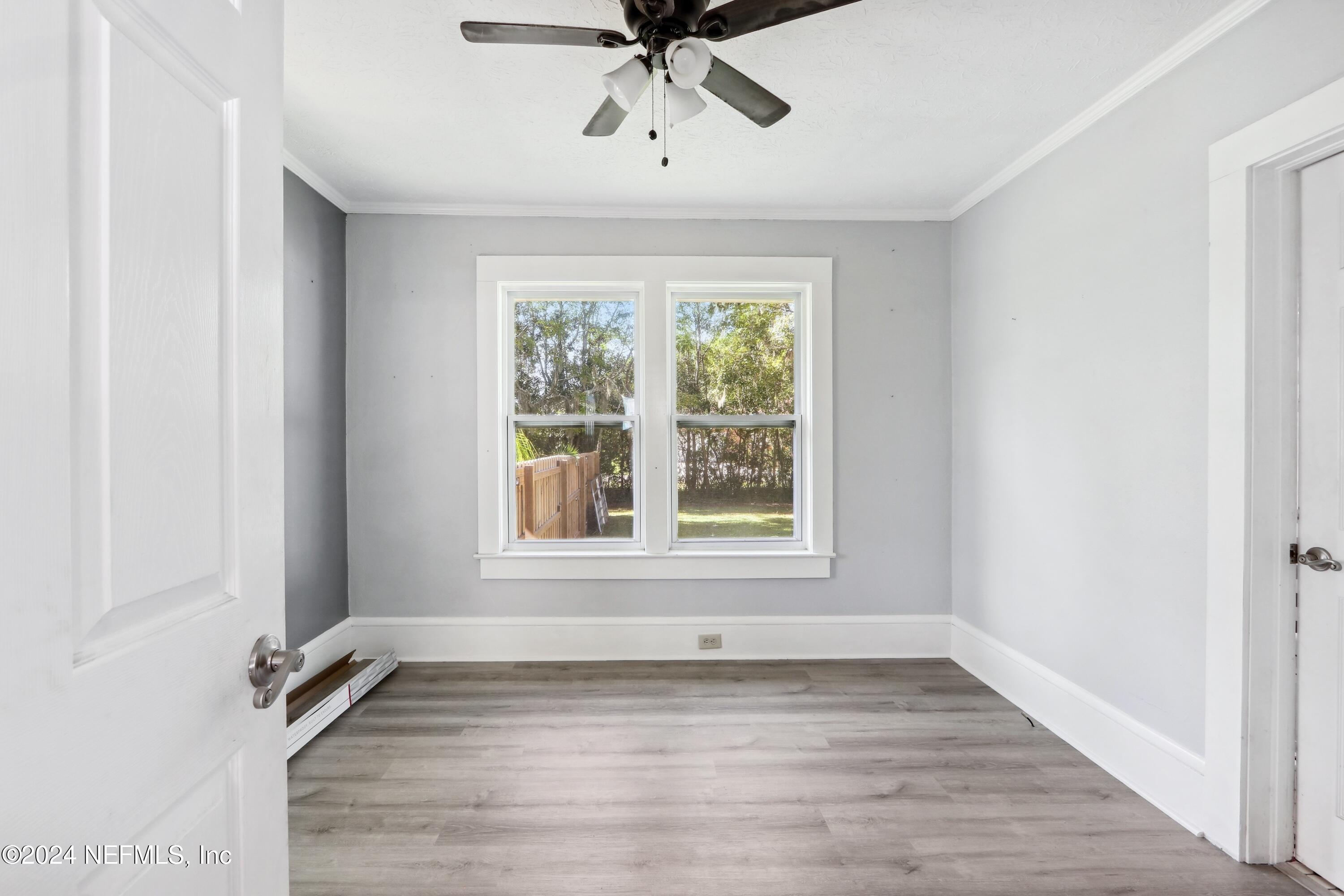 3629 Capper Road Jacksonville, FL 32218 - Photo 7 of 26 an empty room with wooden floor fan and windows
