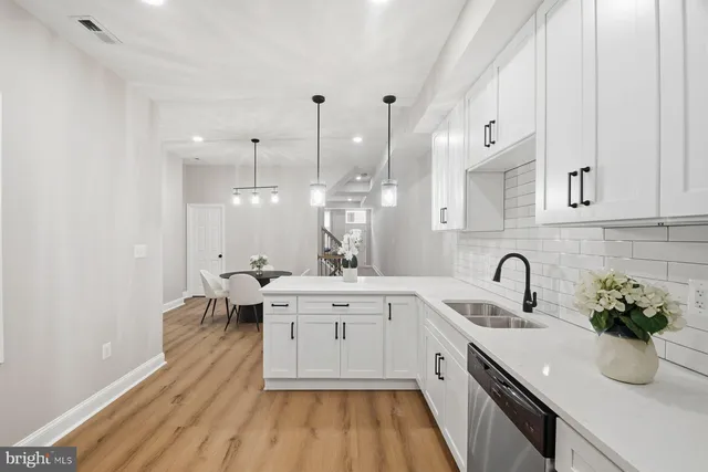 a large white kitchen with a sink and dishwasher a stove with wooden floor