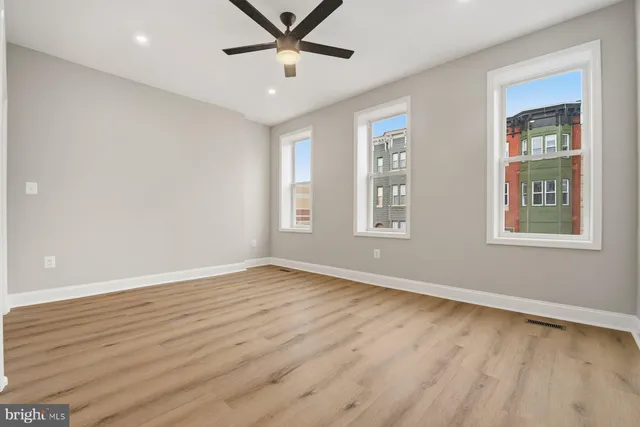 a view of an empty room with window and wooden floor